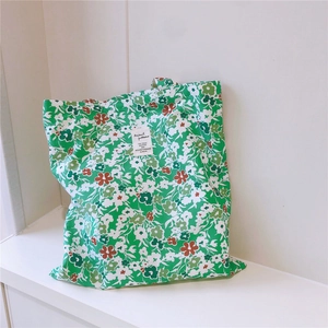 Close-up of green floral cotton canvas tote bag with white woven label and flower print