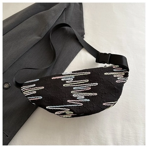 Detail of black crescent chest bag with colorful wave embroidery and textured fabric