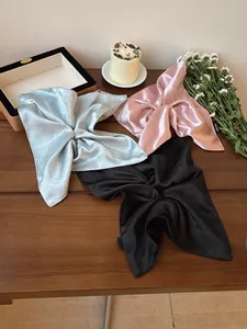 Close-up of glossy satin hair scrunchies with Hand Made labels on a wooden table