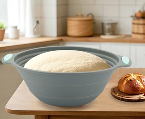 Foldable grey silicone proofing bowl with green handles containing fresh dough