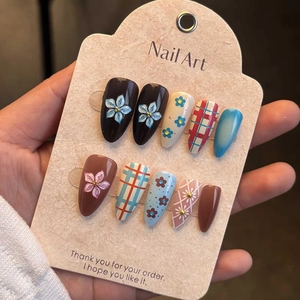 Detailed view of handmade long almond press-on nails with floral and plaid patterns