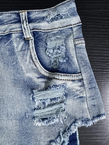 Dettaglio dei bordi sfilacciati e delle tasche distrutte su pantaloncini di jeans blu