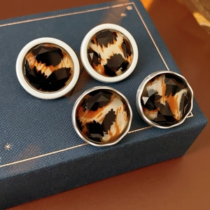Detailed close-up of four leopard print stud earrings on a blue jewelry box