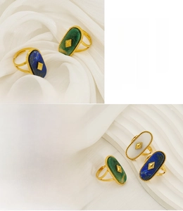 Close-up of vintage oval rings with natural shell and stone inlays on silk fabric