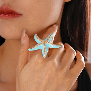 Gold starfish ring with light blue enamel texture worn on finger for beach vacation style