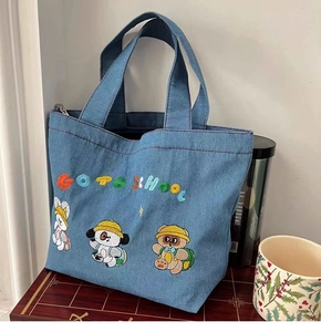Detail of blue denim tote bag with cartoon embroidery and Go To School text
