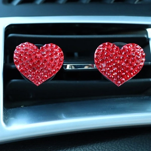 Close-up of dual red rhinestone heart-shaped car air vent clips installed on black grille