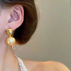 Gros plan sur boucle d'oreille carrée plaquée or 18K avec perle champagne sur mannequin