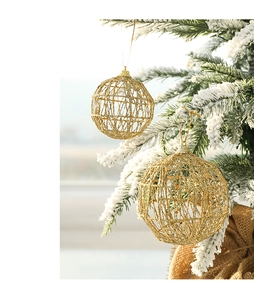Close-up of golden glitter hollow mesh Christmas ball ornament hanging on snowy pine branch