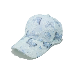 Macro detail of light blue baseball cap featuring textured brushed fabric and butterfly print
