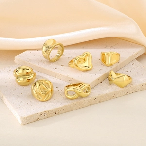 Artistic close-up of seven assorted gold rings with heart and infinity motifs on stone