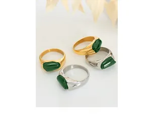 Detailed view of four irregular green stones set on minimalist gold and silver band rings