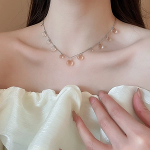 Gros plan du collier argenté avec pendentifs sphériques en résine transparente sur modèle