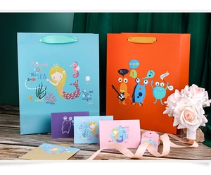 Détail de sacs cadeaux sirène et monstre avec cartes assorties sur une table en bois