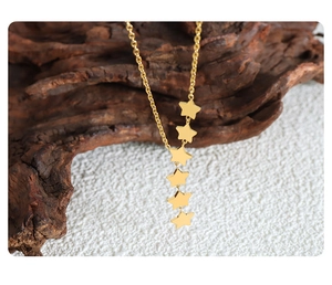 Detail shot of golden necklace with five cascading star pendants on a delicate chain