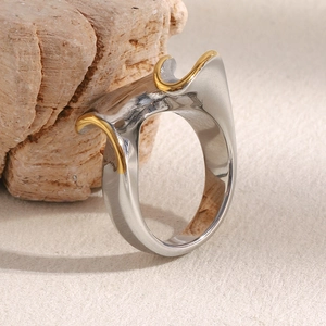 Détail d'une bague ondulée bicolore argent et or posée sur un support en pierre naturelle