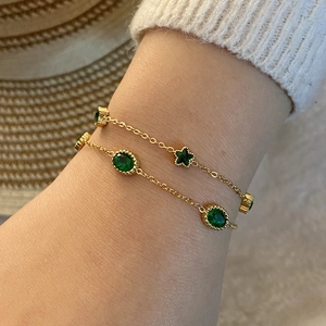 Bracelet vintage doré avec étoiles vert émeraude et breloques cœur sur un poignet féminin