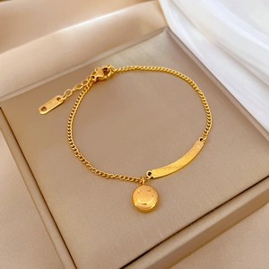 Dettaglio del bracciale dorato in acciaio inossidabile con ciondolo a forma di sorriso