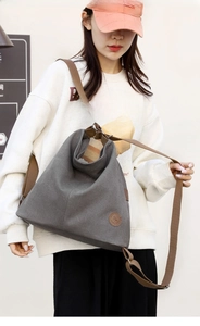 Dettaglio dello zaino in tela grigio scuro con patch logo in pelle e spallacci in cotone
