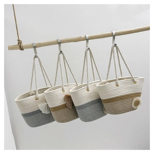 Detail view of four woven tote bags with flower accents hanging on a wooden branch