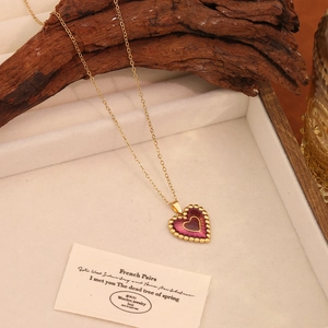 Close-up of vintage heart pendant necklace with purple enamel and gold chain detail