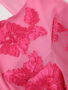 Gros plan d'une robe en tulle rose avec broderies florales 3D et texture détaillée