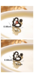 Detail view of heart-shaped steel stud earrings with red and white gemstones