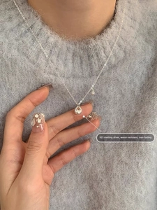 Macro shot of S925 sterling silver chain with circular pendant on a grey sweater
