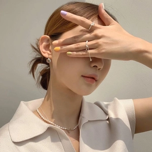 Detail view of 925 silver braided ring and pearl necklace on model in natural lighting