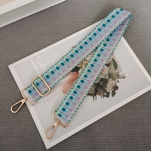 Close-up of mint green and purple woven strap with golden metal lobster clasps