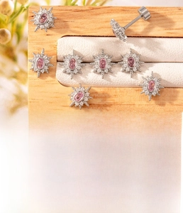 Macro detail of silver starburst cartilage earring with pink zircon and titanium steel stem