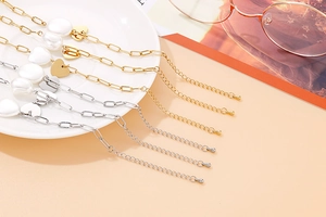 Détail du collier chaîne mixte avec perles et breloque coeur en doré et argenté