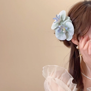 Side view of a light blue ombre fabric flower hair clip with pearl accents on a model