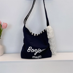 Detail of black canvas tote bag featuring Bonjour print and striped strap with lace scarf
