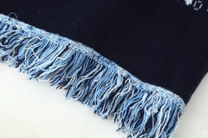 Detailed close-up of blue knit cardigan fabric showing fine texture and fringe tassels