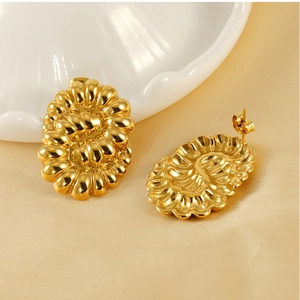Détail macro de boucles d'oreilles dorées 18k avec texture coquillage sur soie