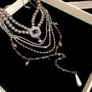Close-up of layered pearl necklace with rhinestone flower pendant and teardrop pearls