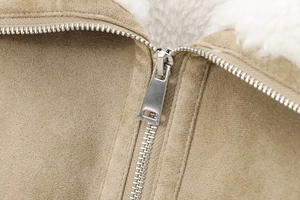 Detailed close-up of khaki suede jacket with white faux shearling lining and silver metal zipper