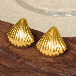Macro view of 18k gold plated shell stud earrings on a rustic dark wood surface