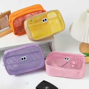 Mesh makeup bags with cartoon eyes in orange, yellow, purple, and pink colors on a desk