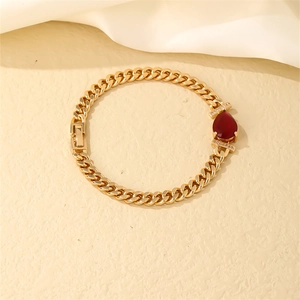 Detailed close-up of gold plated Cuban chain bracelet with a red teardrop zircon gemstone