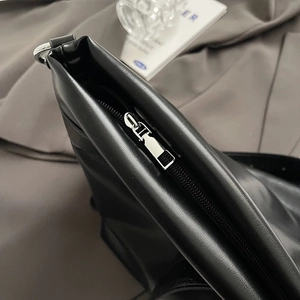 Détail de la fermeture éclair en métal argenté sur un sac fourre-tout en cuir noir chic