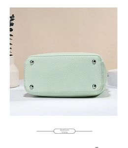Detail view of the light green textured leather bag bottom with silver protective studs