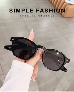 Detail of hand-held round frame sunglasses with silver studs and dark lenses