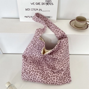 Detailed view of leopard print tote bag with wide strap on minimalist prop stand
