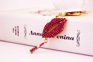 Close-up of a sparkling red rhinestone lips keychain with a gold lipstick pendant charm