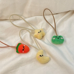 Detail showing plush cartoon strawberry, star, and moon charms on white fabric