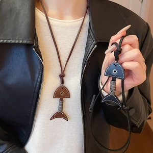 Detail view of fishbone pendants in brown and black leather with metal accents