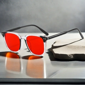 Detail of square sunglasses with red lenses, contrast frame, and silver metal rivets