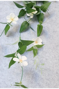 Detail of white bridal hair vine with realistic fabric flowers and green leaves